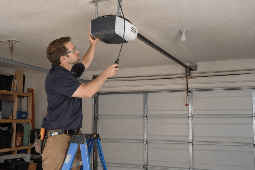 Technician inspecting an unplugged ceiling-mounted garage door opener