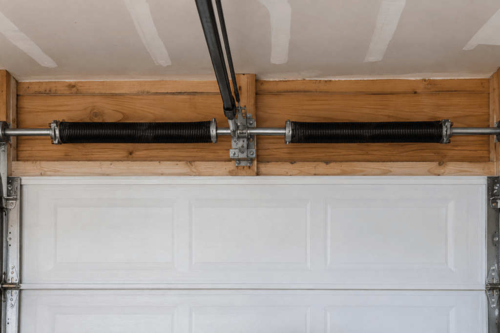 Two torsion springs mounted above a closed white garage door